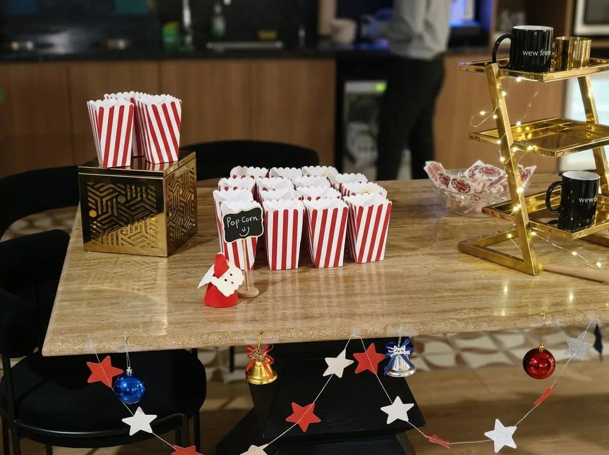Popcorn boxes and gold tiered snack stands set up for an office holiday party