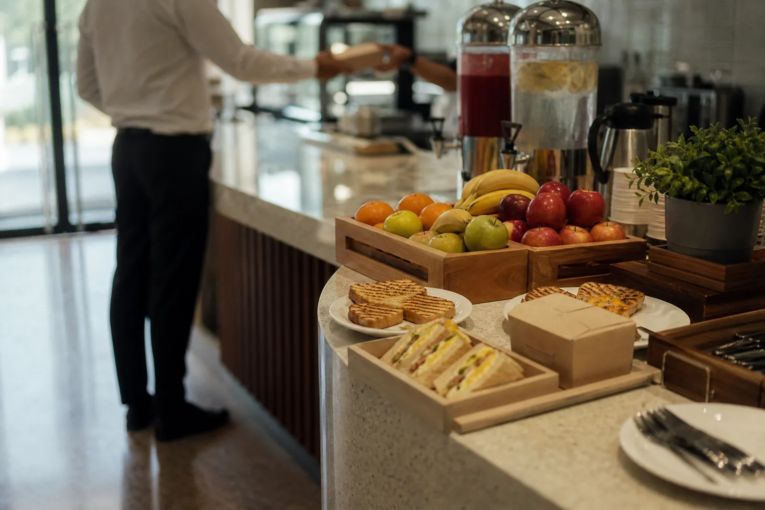 Morning counter set with juice dispensers, fresh fruit, sandwiches and pastries
